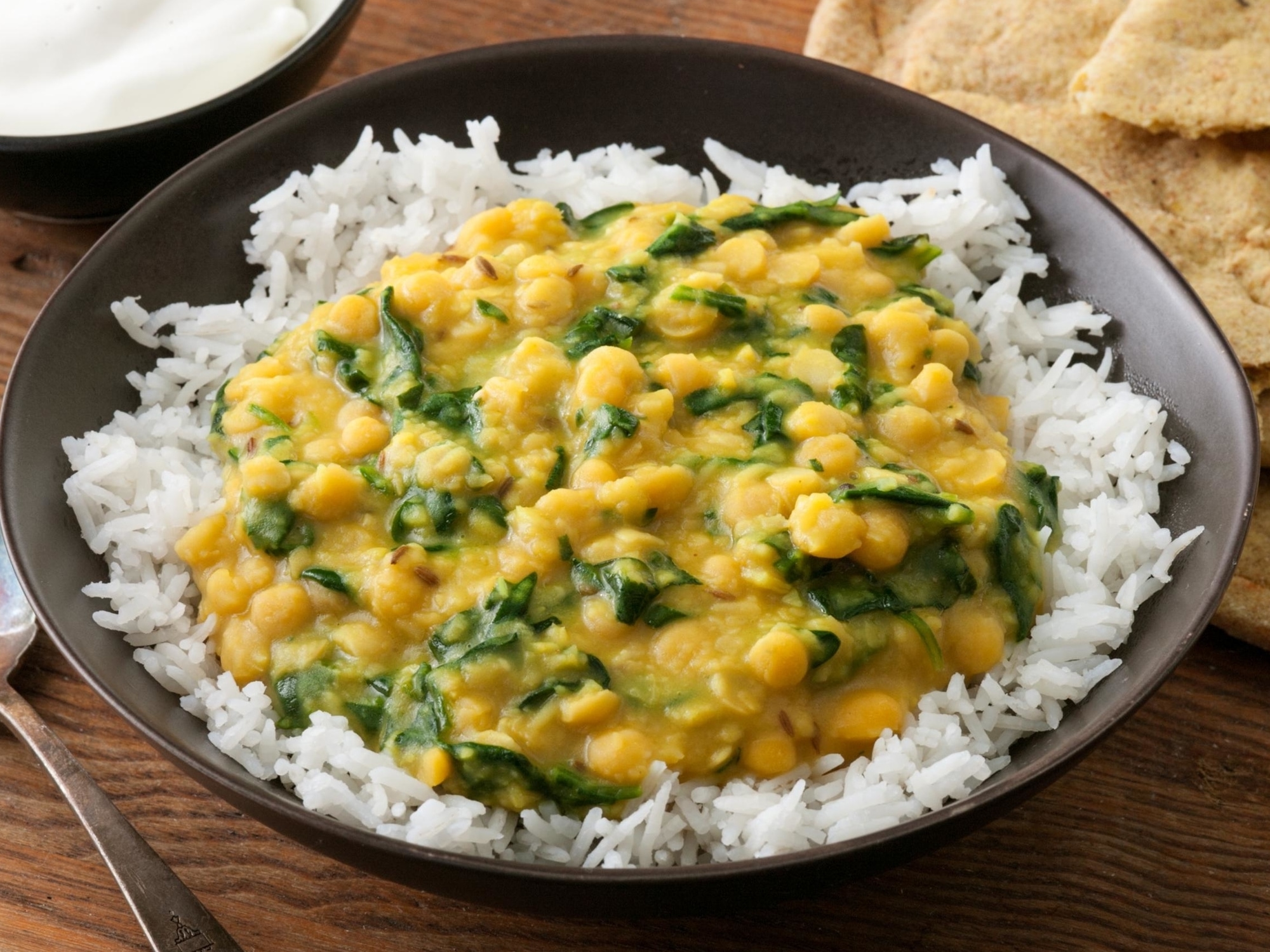 a plate of white rice with a serving of dal with spinach on top