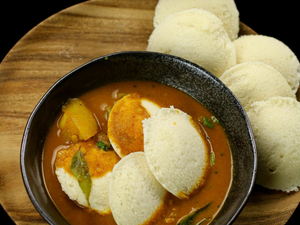 a bowl of sambar on a serving platter with idli