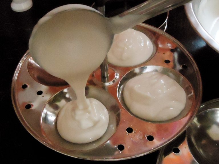 idli batter being poured into a teamer tray