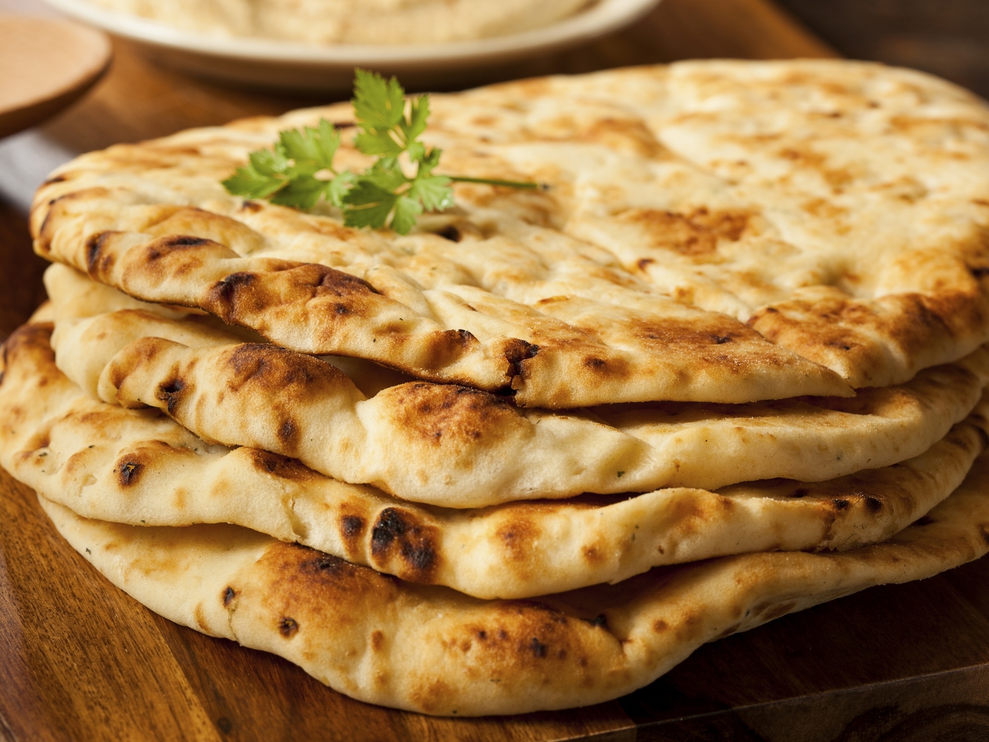 a stack of naan on a wooden platter