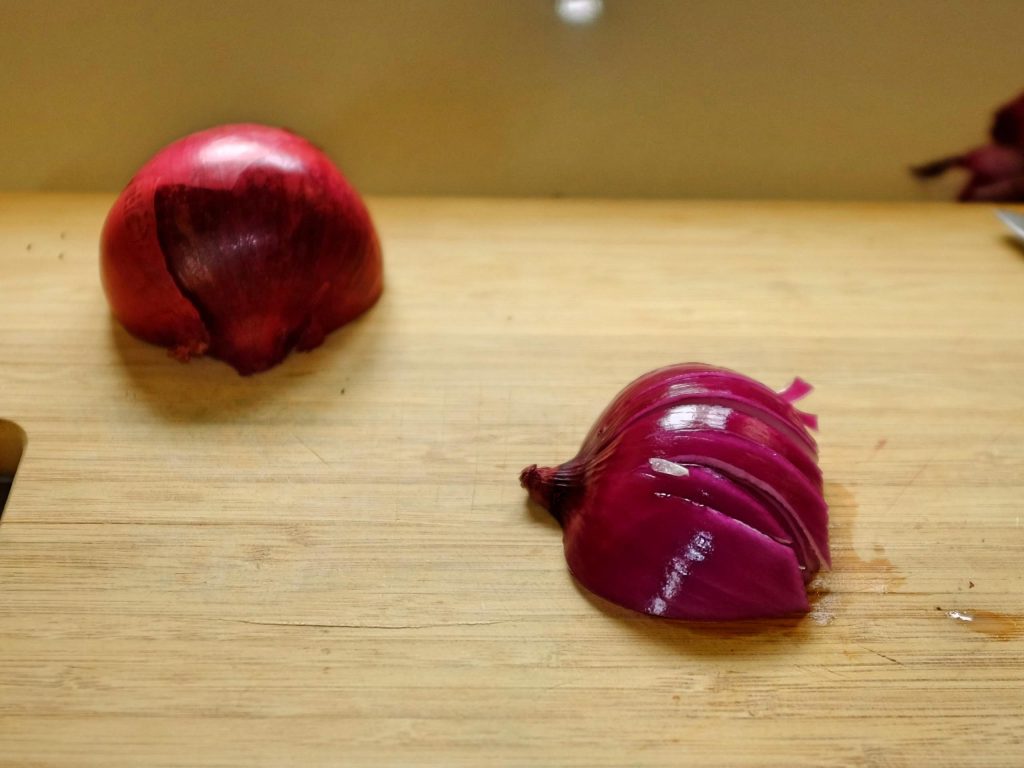 how to chop onions An onion on a chopping board showing first cut from stem end to root.