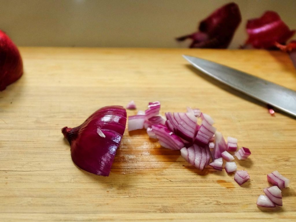 how to chop onions An onion on a chopping board showing second cut across the first cut