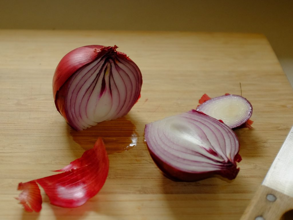 how to chop onions An onion on a chopping board showing the cut to halve the onion.