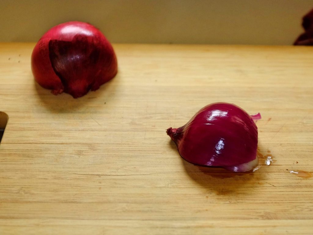 how to chop onions An onion half on a chopping board after peeling paper skin