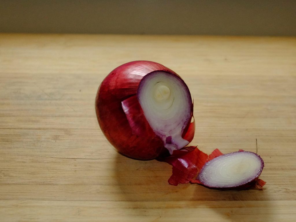 how to chop onions An onion on a chopping board showing the root end removed
