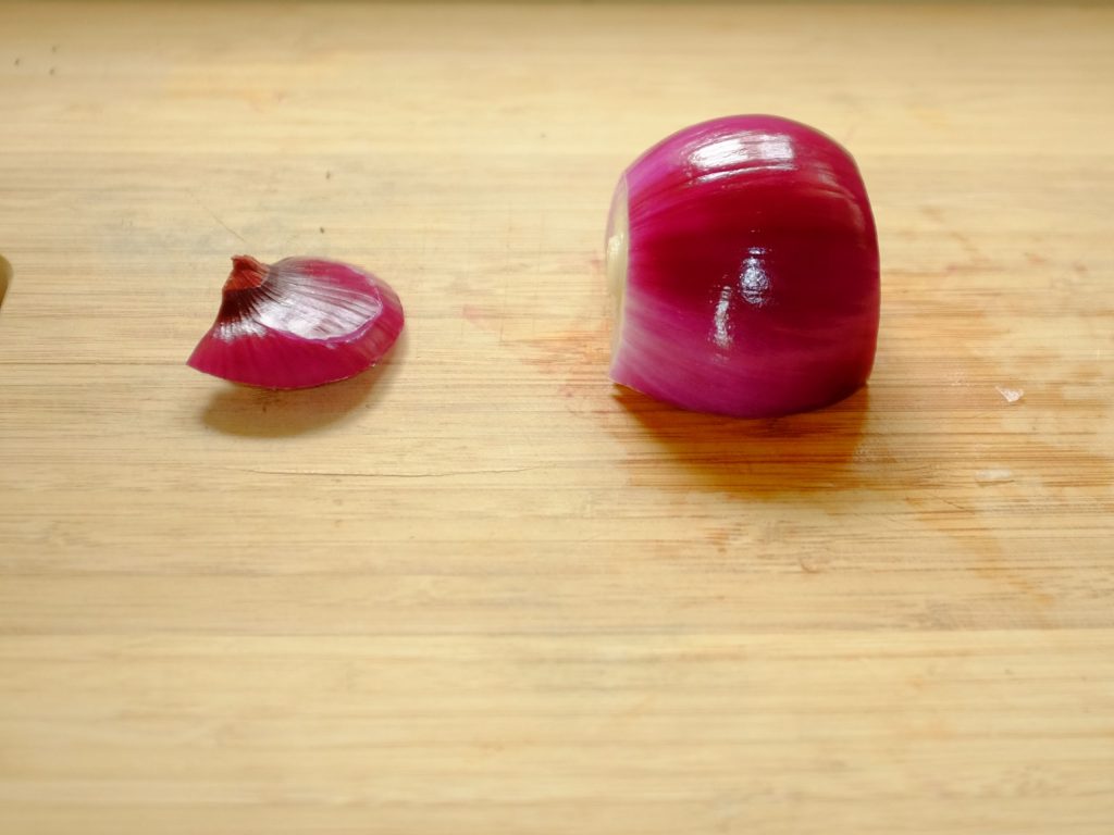 how to slice onions An onion on a chopping board showing the root and stem ends removed