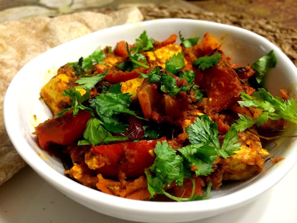 A serving bowl of paneer, capsicum and tomato