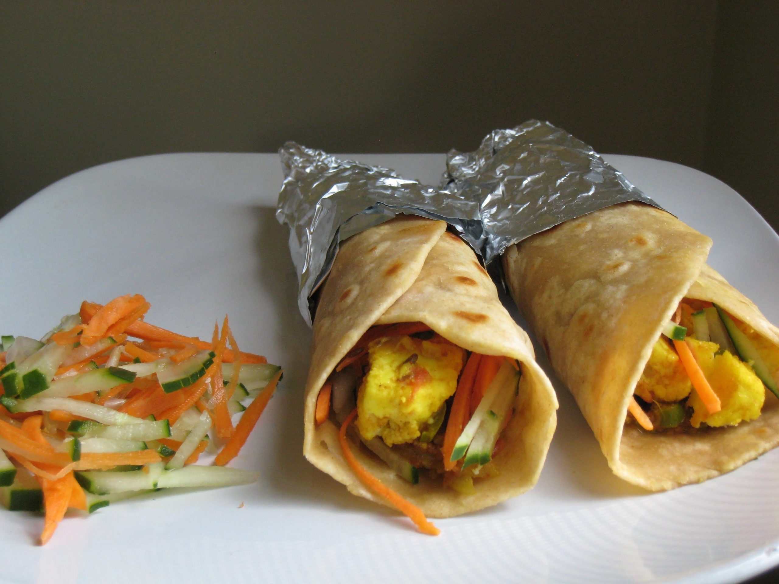 two paneer roti rolls on a plate with a serve of kachumber