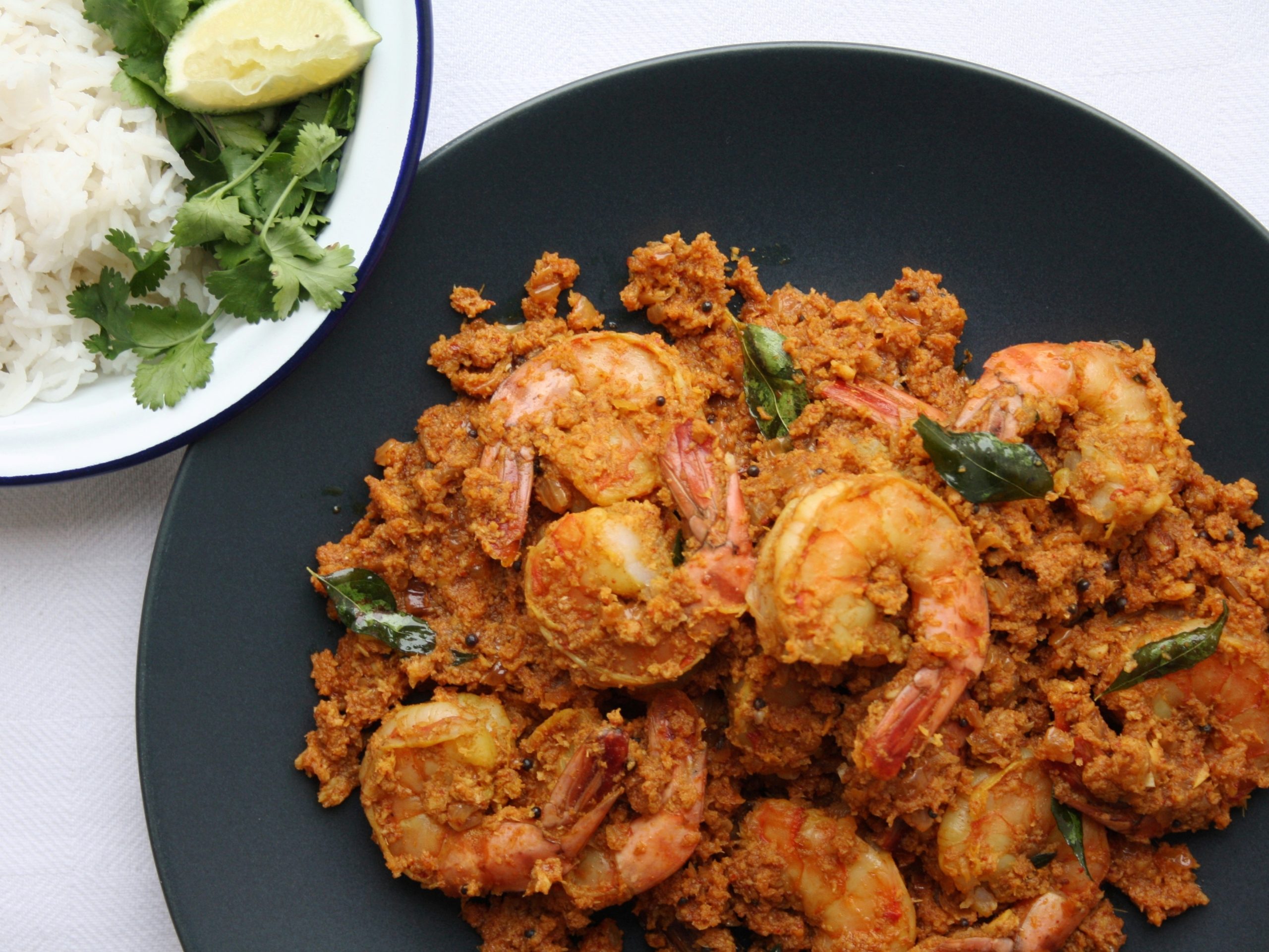 a plate of bengali prawns with a side dish of rice