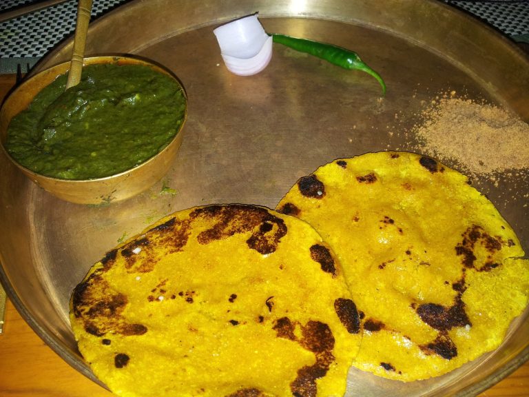 a serving platter of saag and some corn meal roti