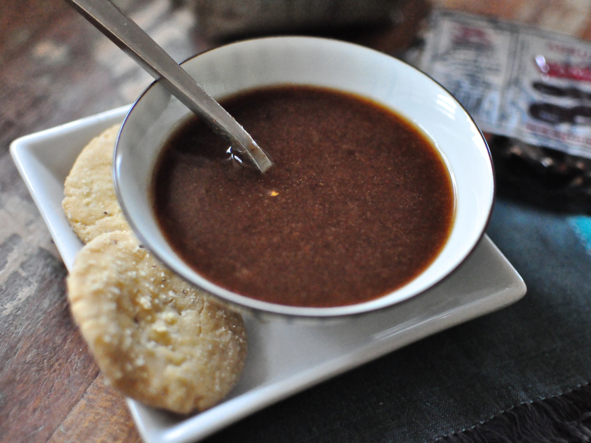 a bowl of tamarind and date chutney with some papdi on the side